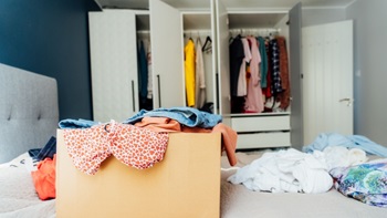 Vestiti in una scatola con letto e armadio aperto